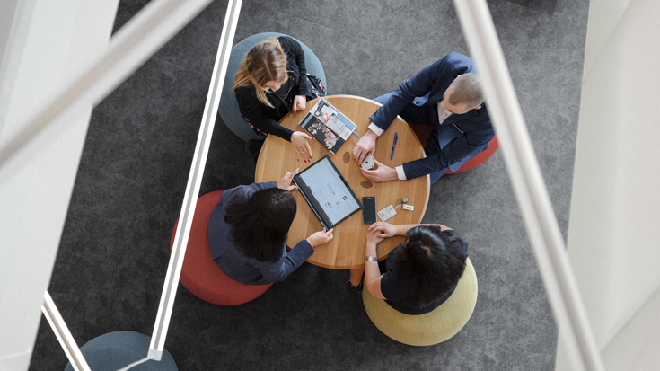 A top view photo of four employees working together around a circular table