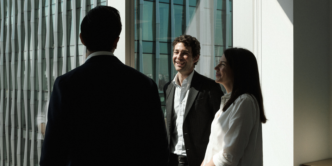 Photo of three employees laughing together in the London's PSP Investments office